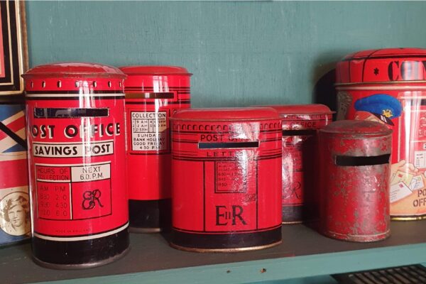 A shelf of vintage red tin postbox moneyboxes