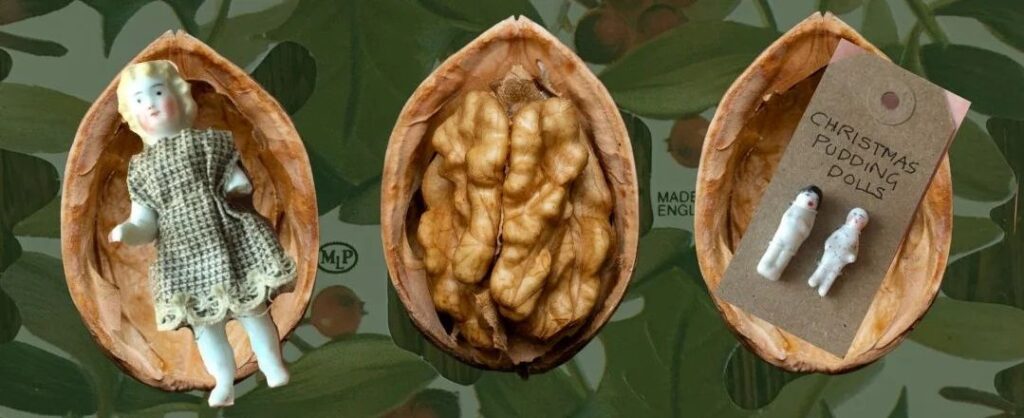 Three halves of walnut shells, the central one containing a walnut, the other two containing very tiny dolls