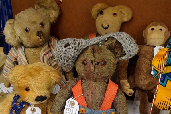 A group of four much loved traditional teddy bears and their friend monkey gazing into the camera hoping you will volunteer