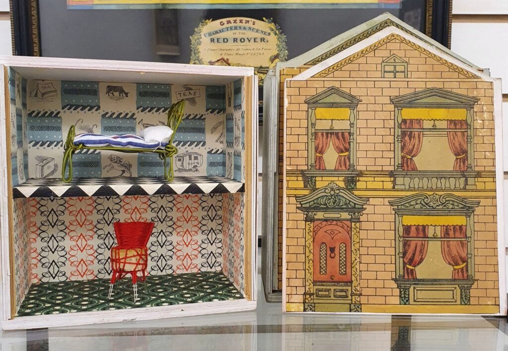 Photo of an original 1960s Redington room-to-let dollhouse, a small wooden two-storey dollhouse with a fading printed facade.