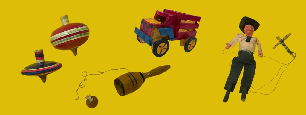 Traditional toys from Mexico, from the collection of Pollock's Toy Museum. From left to right, two spinning tops, a cup and ball game, a painted truck, and a puppet, possibly depicting a mariachi player.