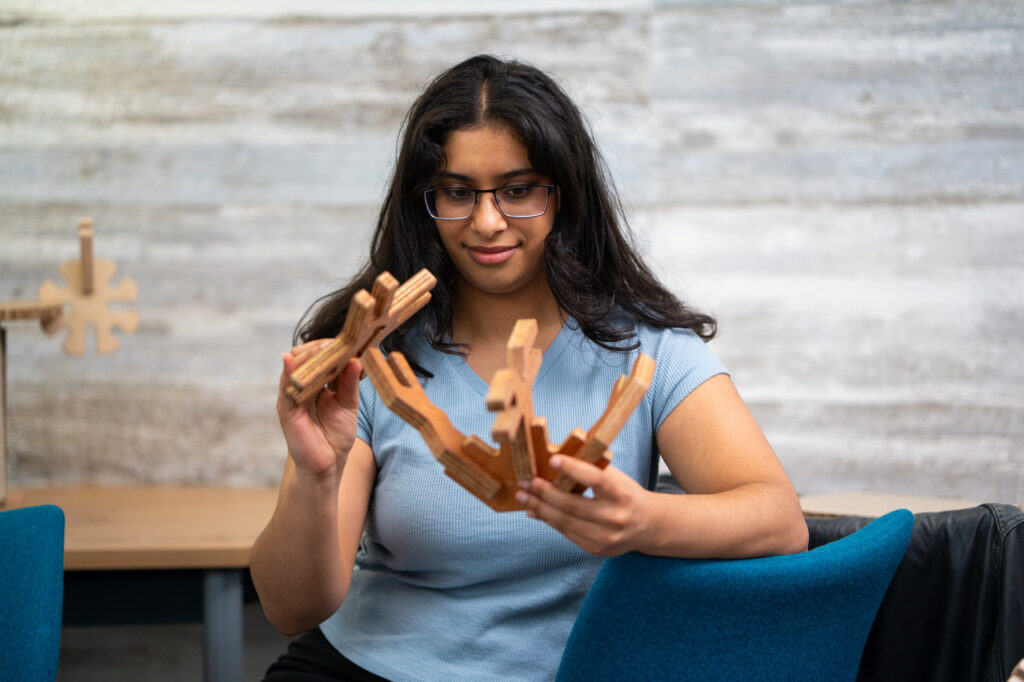 A woman smiles as she looks at a number of large pieces from the abstract Mapl construction kit, and plans how she will link them together.