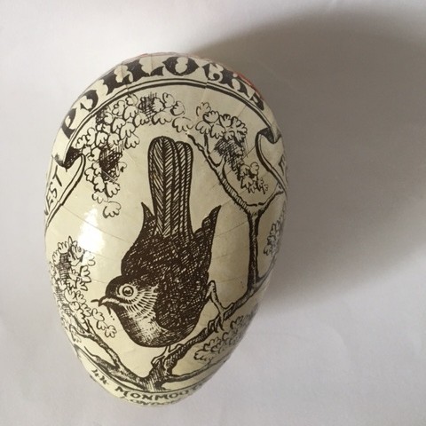 Decorated cream-coloured egg featuring a detailed brown or black line drawing of a bird on a branch, and reading "Pollock's".